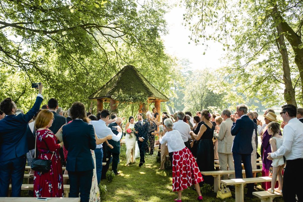 walking down the aisle as guests throw confetti on outdoor garden wedding