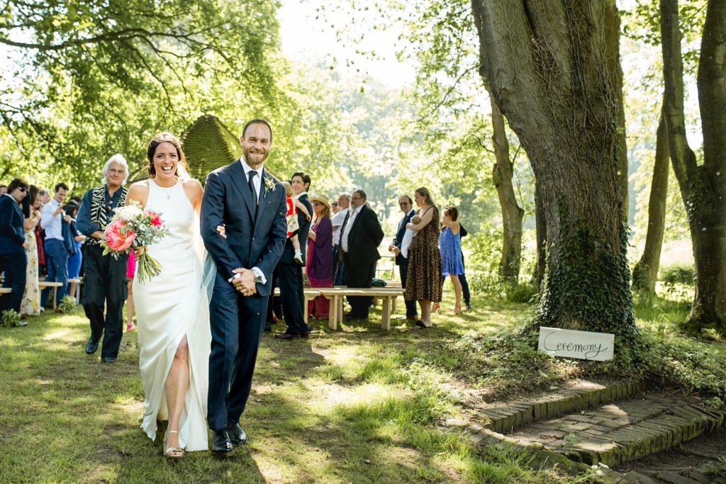 walking down the aisle as guests throw confetti on outdoor garden wedding