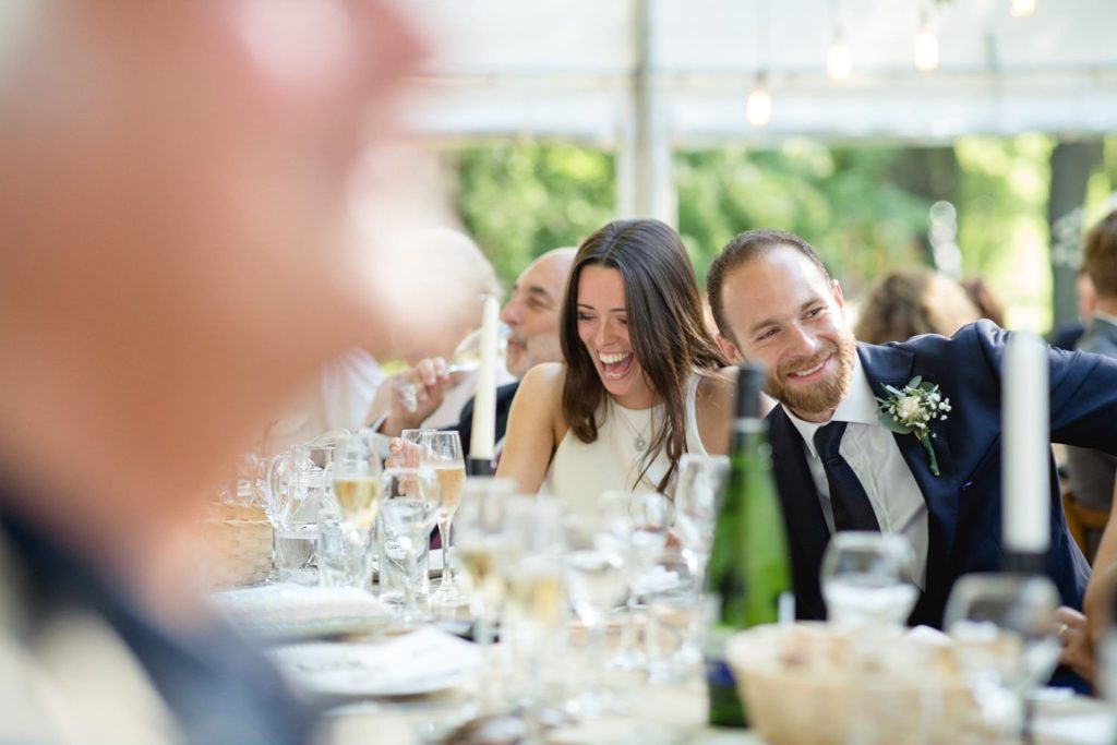 natural photo of bride and groom laughing during wedding speeches 