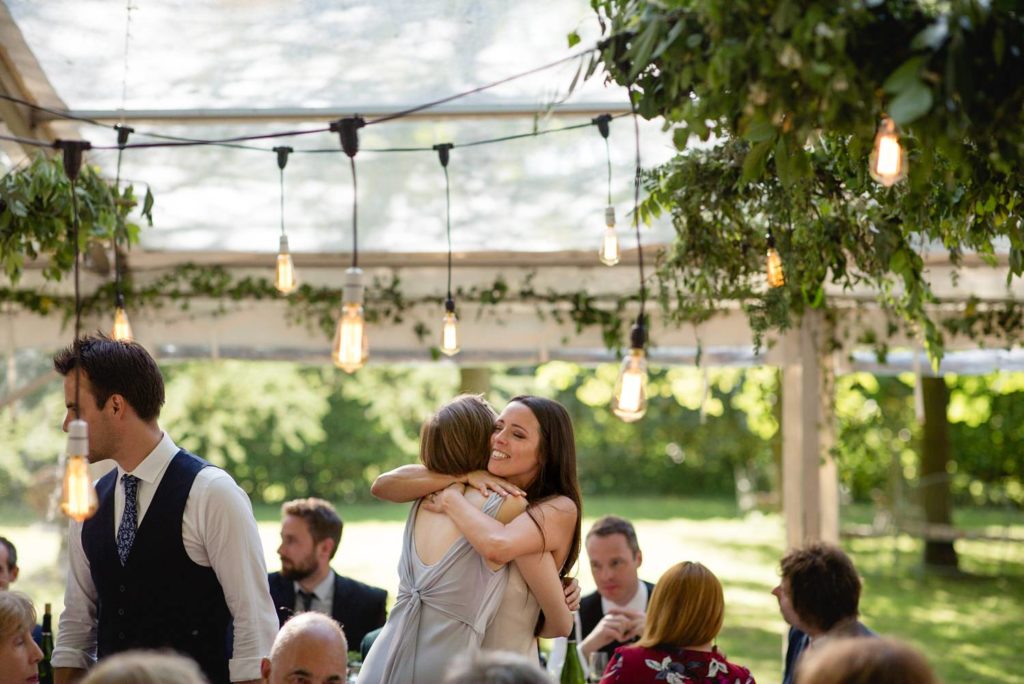 documentary photo of bride hugging sister at her modern outdoor garden wedding